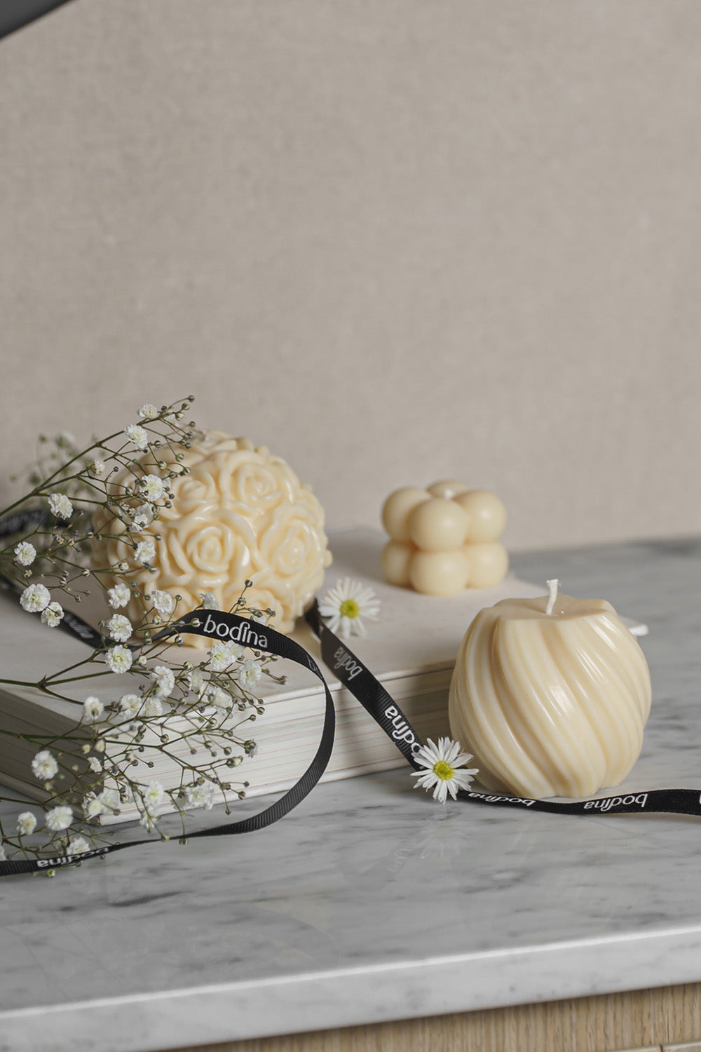 Tres velas decorativas sobre una mesa. 
